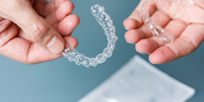 Hands holding transparent aligners. Invisalign orthodontics concept