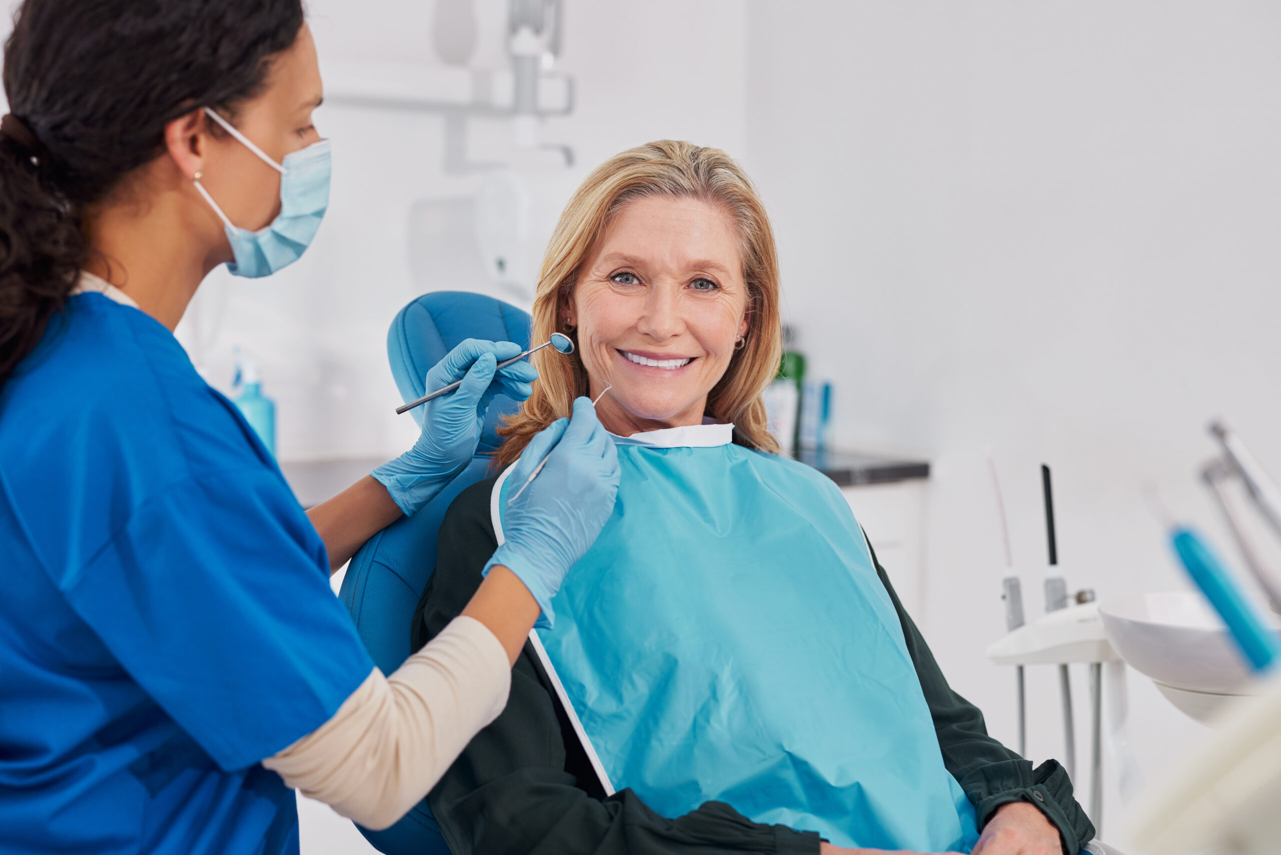 Mature woman smiling with dentures during oral examination at dental clinic. Beautiful elder woman with healthy smile sitting during the consultation with dentist at the dental office. Happy elderly female patient smile for tooth whitening treatment.