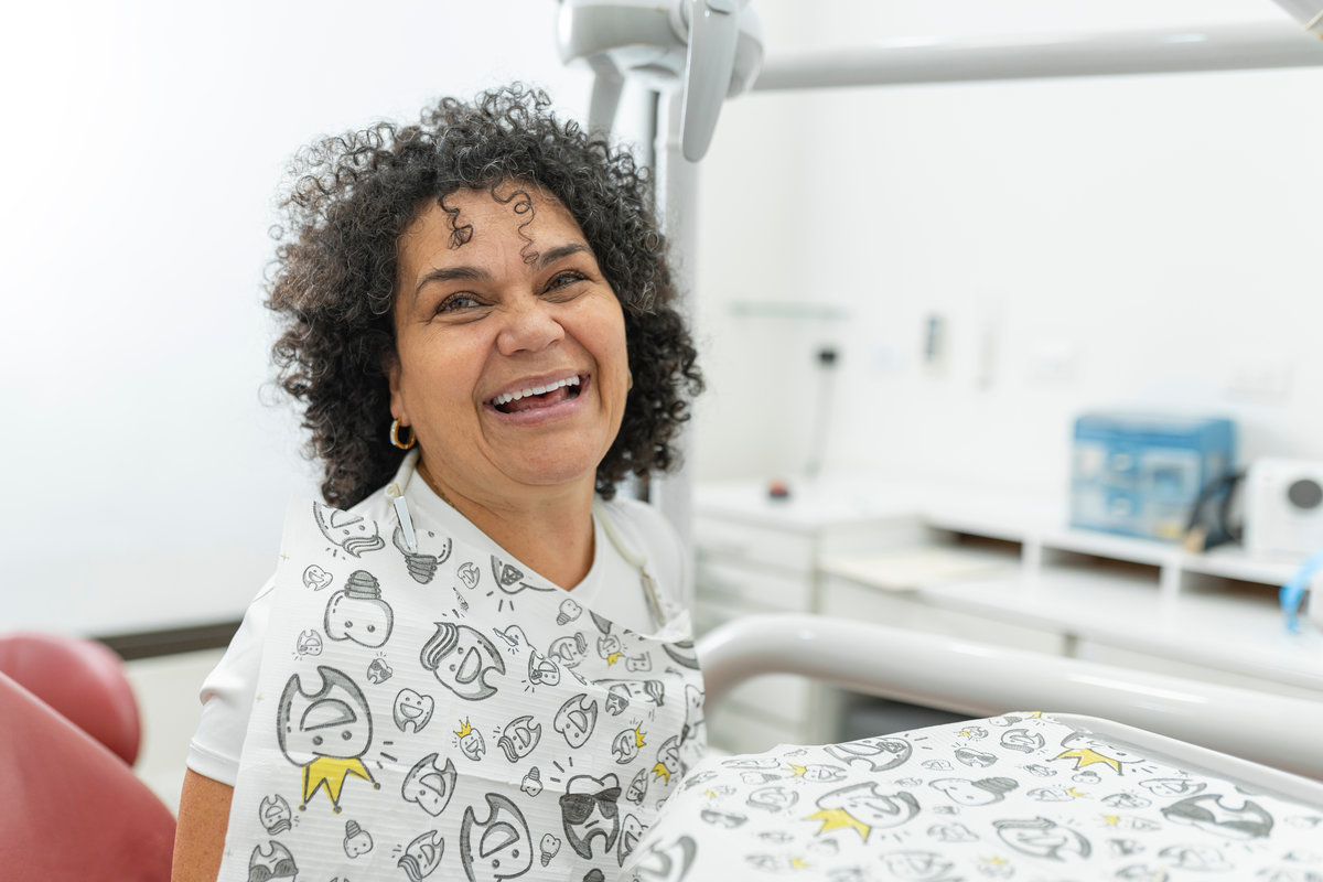Happy smiling patient sitting in a dental chair after treatment