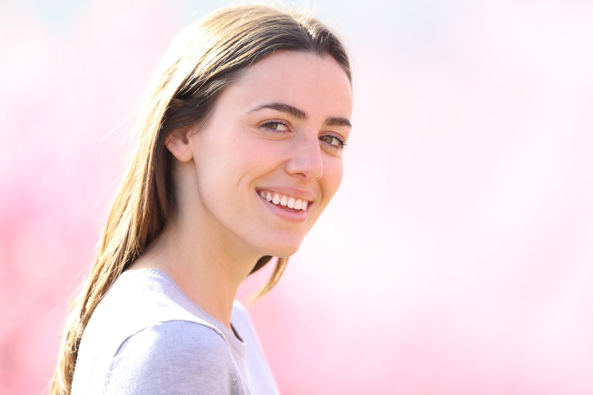 Beautiful woman with perfect smile looking at camera in a pink field