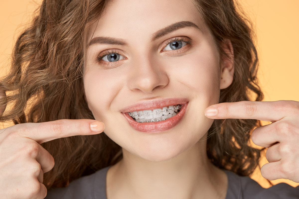 curly hair woman with brackets on biege background close-up