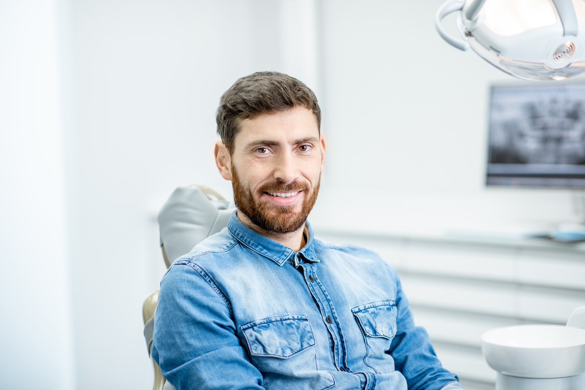 Portrait of a handsome bearded man with healthy smile in the dental office